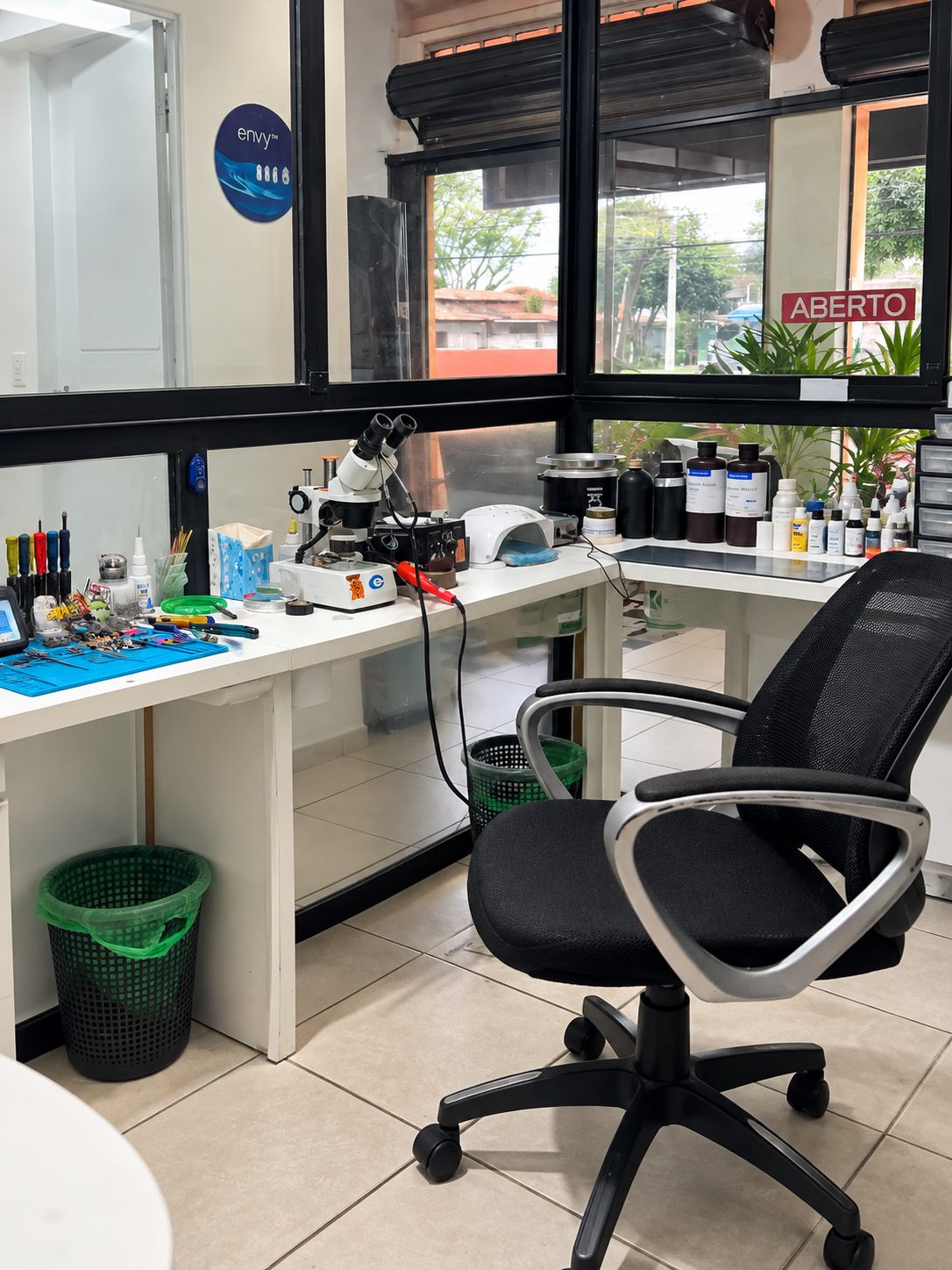 Bancada do laboratório da AudioVic com microscópio, lupa de bancada e produtos técnicos