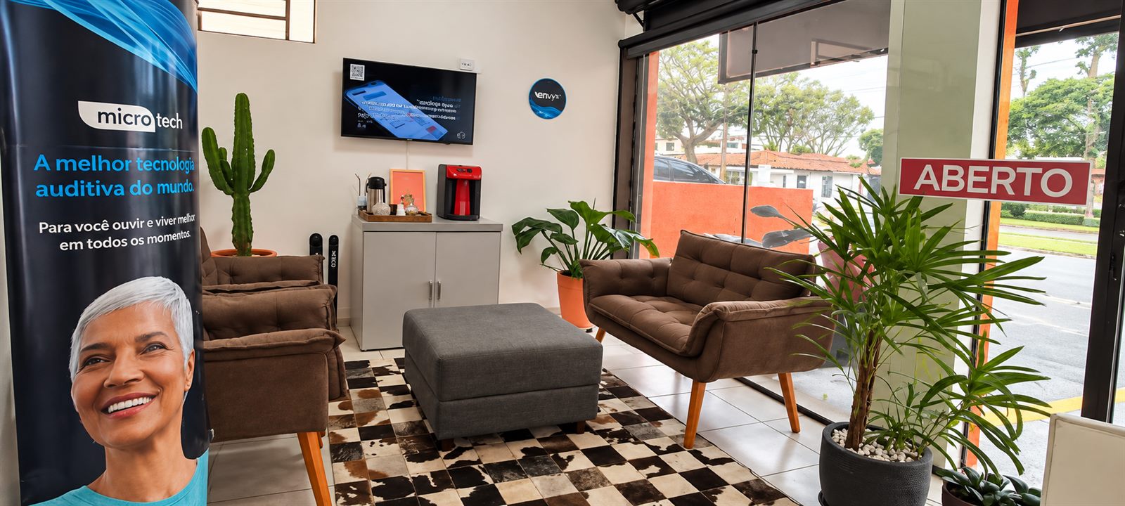 Recepção da AudioVic com poltronas, televisão e balcão de atendimento
